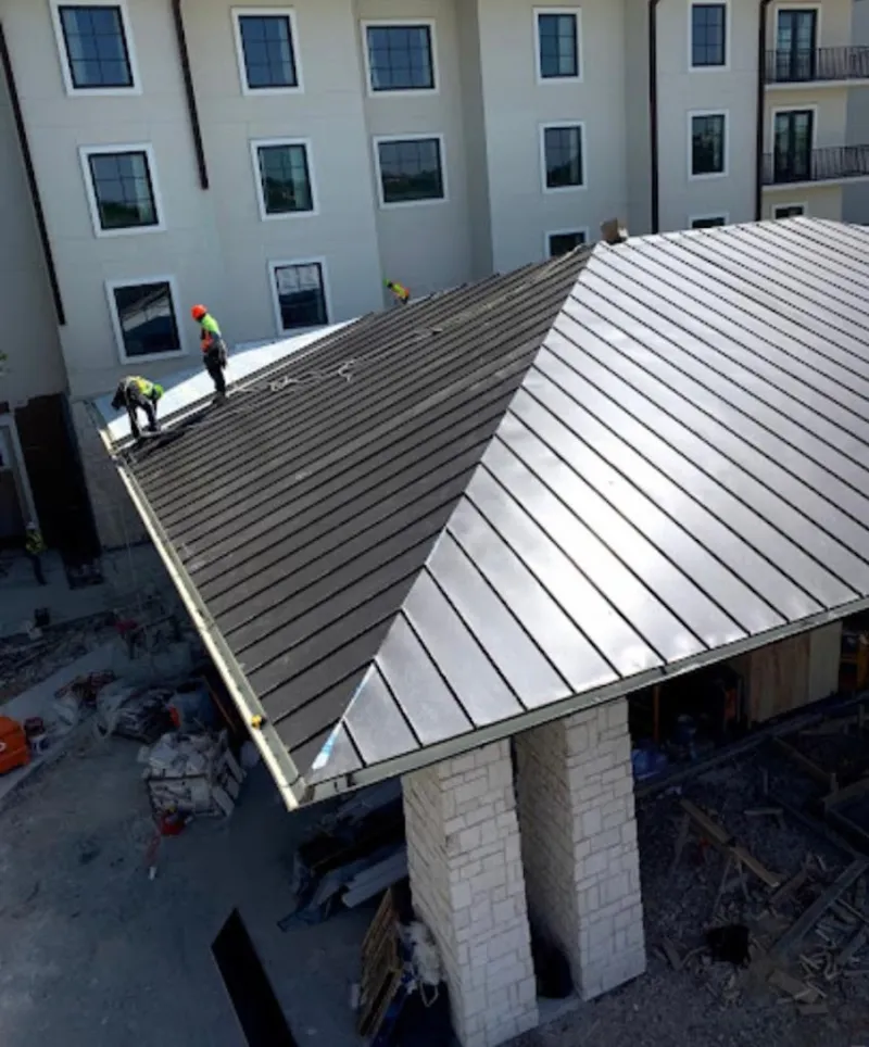 Crew installing standing seam metal roof panels on a commercial project in Azalea Park